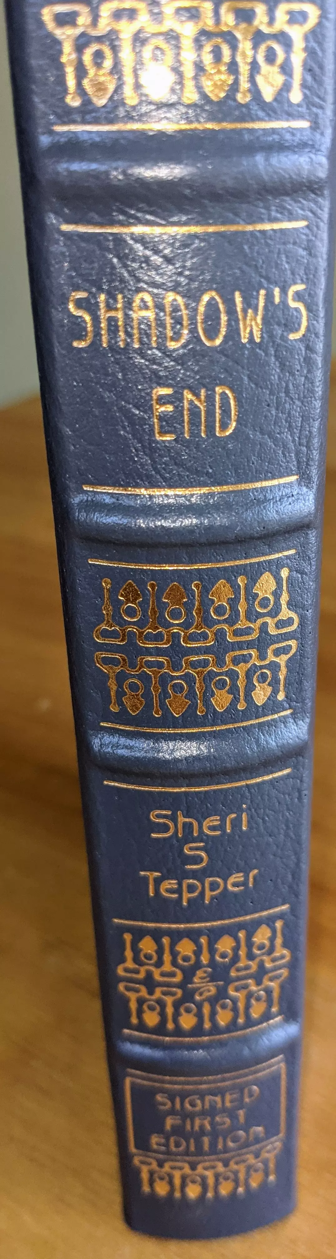 SIGNED, FIRST EDITION, FIRST PRINTING, Pristine, leather-bound Collector Edition of Shadow's End by Sheri S. Tepper, published by The Easton Press in 1994 as part of The Signed First Editions of Science Fiction Collection. Introduction by James Gunn
 - 
Beautifully bound in creamy blue leather, with elegant 22k gold-foil embossing. At the top and bottom sections of the spine are intricate gold-embossed designs resembling repeating symbols of stylized figures or ornate keys. The book's title, Shadow's End, appears in gold uppercase letters in the center of the spine. Below the title, the author's name, Sheri S. Tepper, is embossed in gold in a slightly smaller font.
 - 
Further down, a rectangular gold-embossed label states SIGNED FIRST EDITION in capital letters, surrounded by decorative designs similar to those found at the top and bottom of the spine. The spine itself features hubbed spines, which add a classic, textured appearance.
 - 
The pages are printed on archival-quality, acid-neutral paper. The page edges are 22k gold gilded. Inside, the book includes a pristine bookplate and features an original frontispiece artwork by Jill Bauman. The smyth-sewn binding ensures durability, while concealed muslin joints provide additional structural integrity
 - 
Meticulously preserved in a dust-free bookcase within a dry climate by a single private owner, this volume remains in pristine condition
 - 
A stunning and rare collectible!