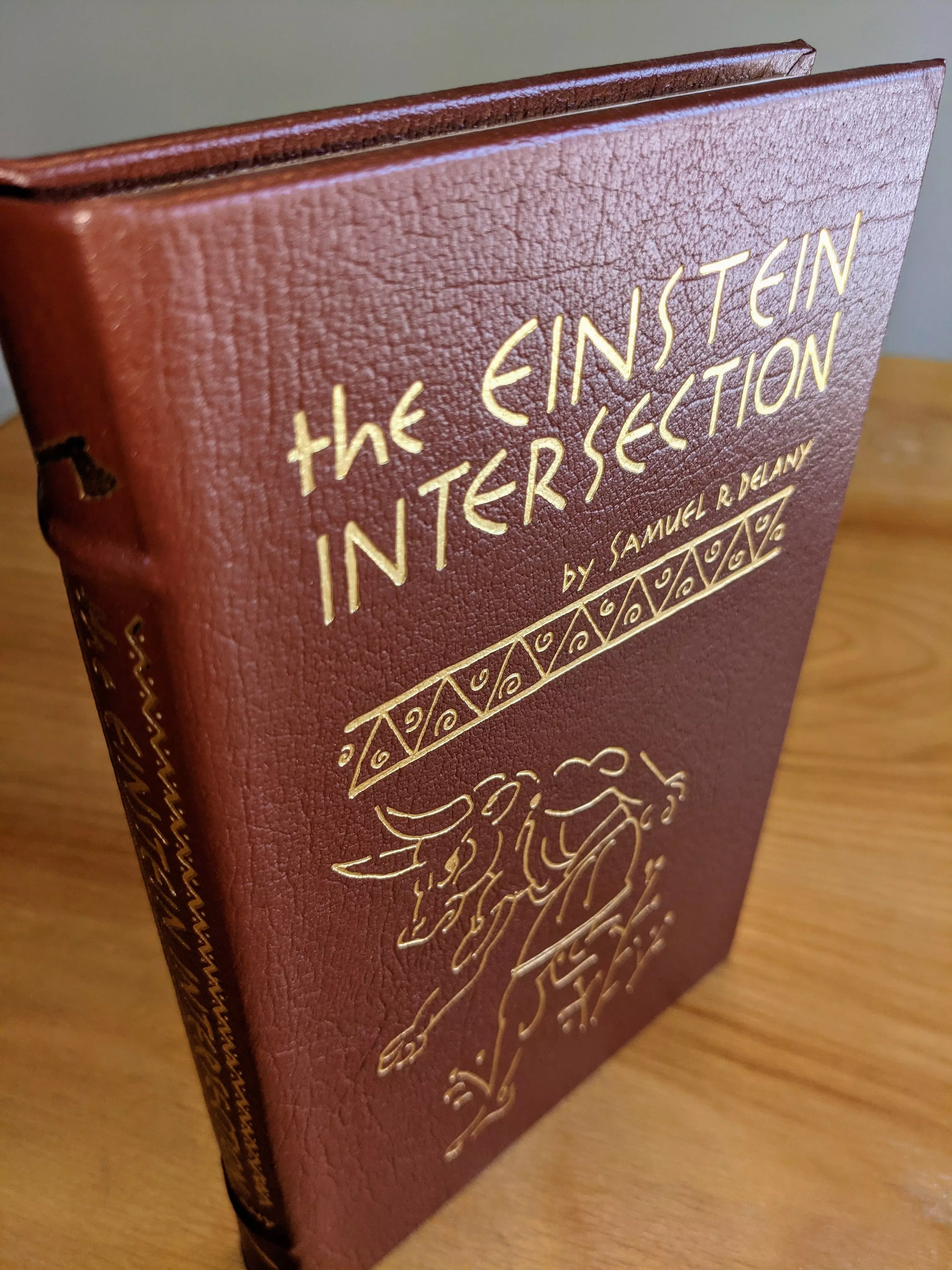 Pristine, leather-bound Collector Edition of the Einstein Intersection by Samuel R. Delany, published by The Easton Press in 1986 as part of Masterpieces of Science Fiction Collection. Introduction by George Zebrowski and illustrated by Frank Mayo.
 - 
Beautifully bound in chocolate colored leather, with elegant 22k gold-foil embossing. The title, is prominently displayed on the front cover in elegant, stylized 22k gold lettering, accompanied by the author's name. Below the title, is a decorative geometric border and a detailed illustration of a Minotaur.
 - 
The spine has the title and author's name in gold serif font, framed by intricate geometric patterns. The binding is full leather with raised hubbed spines. The book is accented in 22kt gold and printed on high-quality, acid-neutral archival paper with gilded edges, providing both visual brilliance and lasting preservation. The smyth-sewn binding ensures durability, while concealed muslin joints provide additional structural integrity
 - 
This volume is a book club 1st edition, maintained in pristine condition as part of a single-owner private collection. It has been stored unread in dust-free bookcases within a dry climate. Inside the front cover is a pristine, untouched bookplate, further emphasizing its exclusivity and collectible value.
 - 
A stunning and rare collectible!