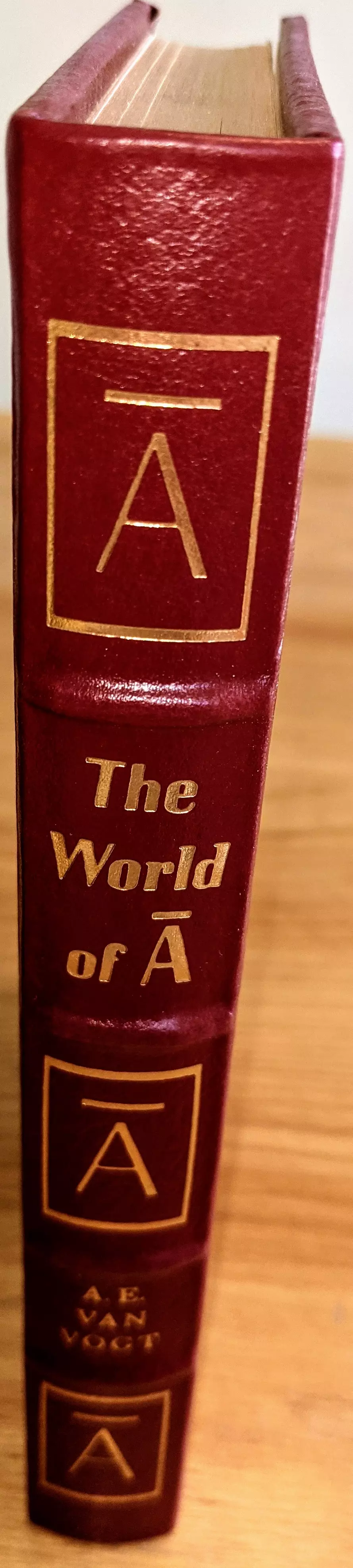 The spine of this book is bound in rich, reddish-brown leather with gold embossed lettering and symbols. At the top, there is a gold-outlined square containing a large capital 'A' with a horizontal bar above it, representing the 'Null-A' symbol. Below that, the title The World of A is centered in gold, with the distinctive 'Null-A' character. Further down, the author's name A. E. VAN VOGT is also embossed in gold. The spine is divided into sections by subtle horizontal ridges, and both the top and bottom sections feature the same gold square with the 'Null-A' symbol, creating a symmetrical and visually striking design