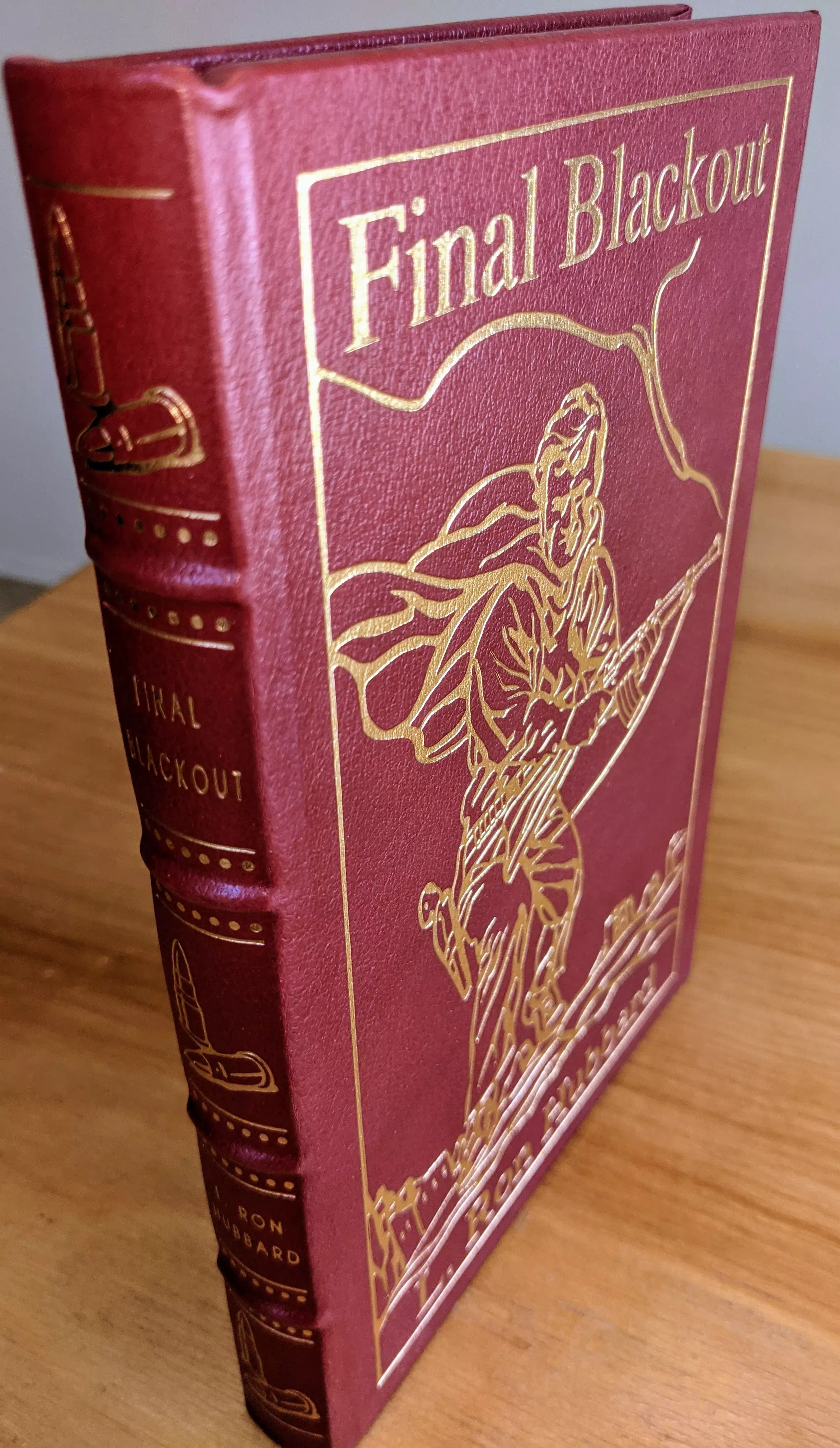 Stunning collector's edition of Final Blackout by L. Ron Hubbard (1993), part of the Masterpieces of Science Fiction Collection by The Easton Press
 - 
The cover features 22kt gold-embossed original artwork from the L. Ron Hubbard Library. The intricate design depicts a determined soldier in action, with flowing details capturing the intensity of the story's dystopian setting. The artwork is framed by a simple yet elegant gold border, accentuating the dramatic imagery and adding a refined touch
 - 
Bound in rich red full leather, the book exudes a sense of luxury and durability. The hubbed spine is adorned with additional gold accents, including a bold title, Final Blackout, and the author's name, further emphasizing its collectible nature
 - 
This edition is printed on archival-quality acid-neutral paper with 22k gold gilded edges, lending a shimmering elegance while ensuring the preservation of its pages. The smyth-sewn binding and concealed muslin joints ensure exceptional structural integrity, allowing the book to lie flat when opened
 - 
Maintained in pristine condition, this volume comes from a single-owner private collection, carefully stored in dust-free bookcases in a dry climate. It includes a pristine bookplate on the inside front cover, adding to its exclusivity and appeal for collectors
 - 
A striking combination of design and storytelling, this collector's edition of Final Blackout is a must-have for enthusiasts of science fiction and fine bookmaking alike