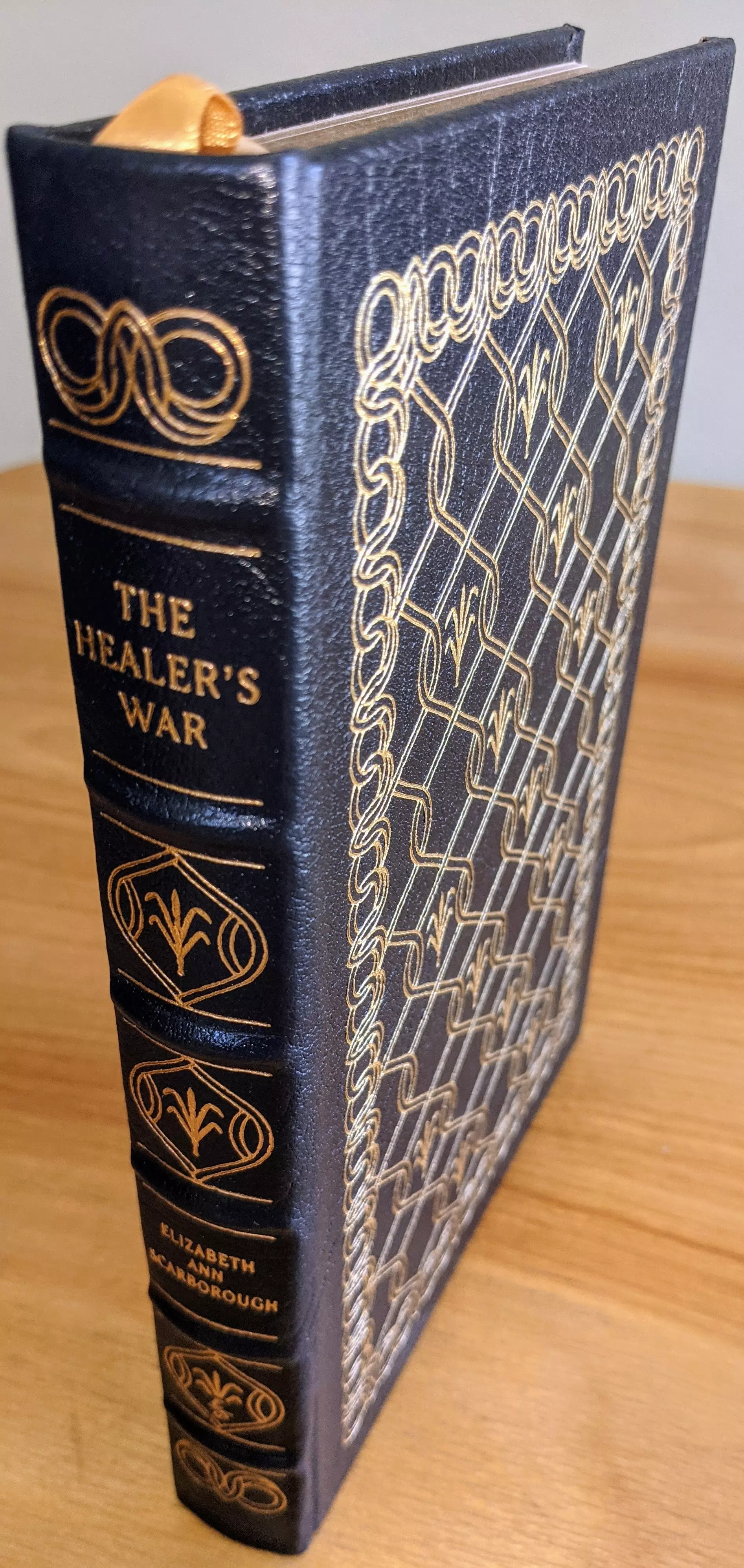 This exquisite Collector's Edition of The Healer's War by Elizabeth Ann Scarborough is a rare and pristine volume from The Easton Press Masterpieces of Science Fiction Collection. Bound in luxurious dark navy blue leather, the book exudes elegance with its intricate 22kt gold accents adorning the cover, spine, and edges. The elaborate golden filigree design on the front and back, along with the hubbed spine, gives it a timeless and classic aesthetic
 - 
Crafted with the highest archival standards, this limited-run edition is printed on acid-neutral archival paper with 22k gold gilded page edges, ensuring durability and preservation. The smyth-sewn binding and concealed muslin joints contribute to its strength and longevity. Inside, a pristine, unused bookplate is affixed to the inside of the front cover, adding to its collector's appeal
 - 
This copy comes from a single-owner private collection, stored in dust-free bookcases in a dry climate, and remains unread and in pristine condition. It features stunning original artwork by Frank Kelly Freas, enhancing its value as both a literary and artistic masterpiece. Introduction by Pamela Sargent. This is an As New collector's gem, perfect for those who cherish finely bound science fiction classics