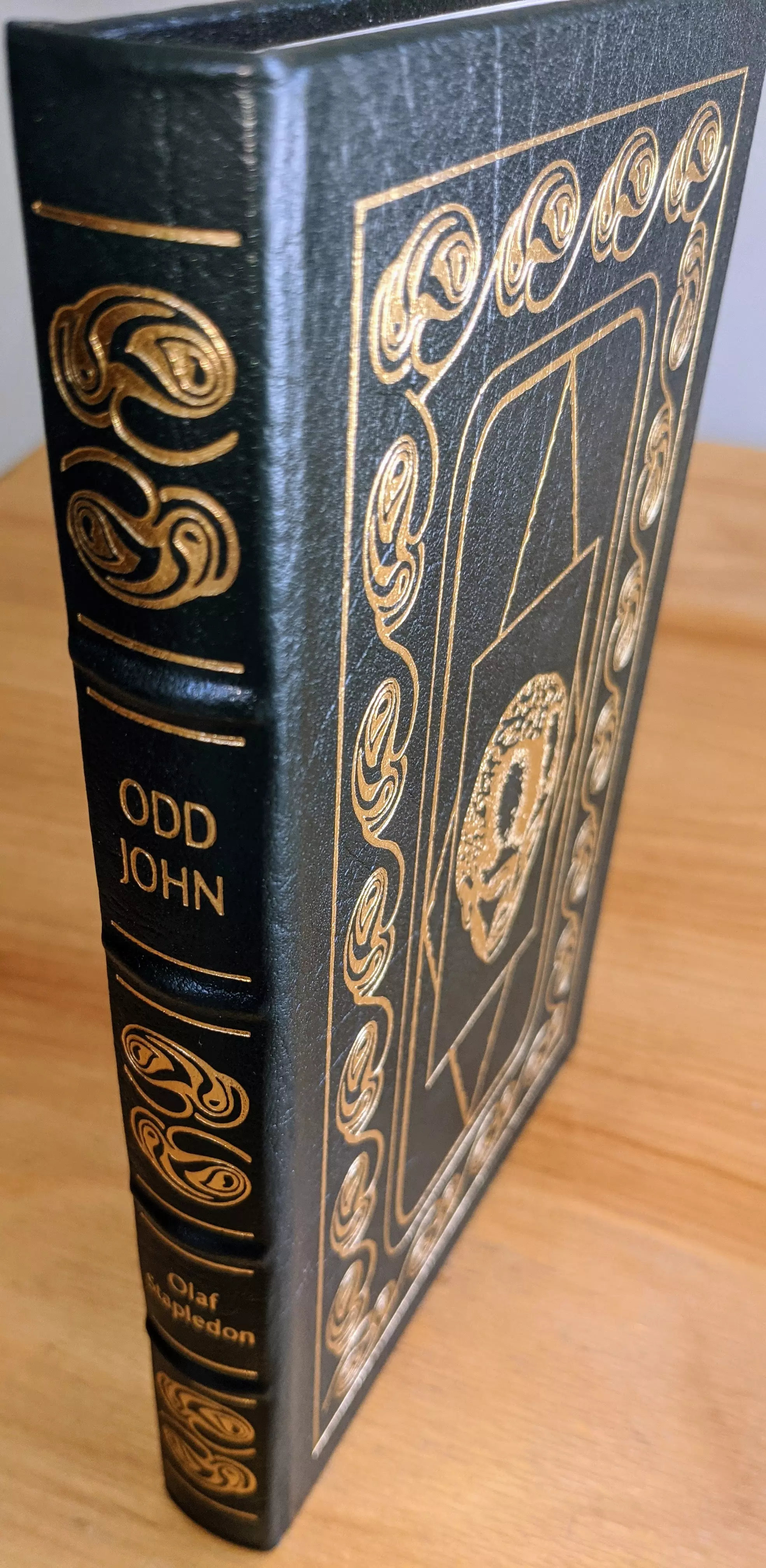 Stunning collector's edition of Odd John by Olaf Stapledon, published by The Easton Press as part of their Masterpieces of Science Fiction Collection, is beautifully bound in luxurious dark green leather. Illustrated by Wendy Snow-Lang, intricately accented with radiant 22kt gold detailing, displaying ornate, abstract designs framing a stylized, enigmatic figure at the center. The detailed 22k gold embossing creates striking visual contrasts, highlighting the meticulous craftsmanship of this limited-run volume.
 - 
The book's spine is hubbed, accented with golden embellishments, and clearly displays the title ODD JOHN and author Olaf Stapledon in crisp, gold lettering. Printed on high-quality acid-neutral archival paper, the book includes carefully 22k gold gilded page edges, enhancing its timeless appeal and preservation quality. Expertly bound using traditional smyth sewing and concealed muslin joints, this volume ensures remarkable durability and structural integrity
 - 
Inside, the book features an insightful introduction by acclaimed author Alfred Bester, further enhancing its literary value. A pristine, unused bookplate is neatly positioned inside the front cover, ready for personalization
 - 
From a single-owner private collection, the book has been meticulously stored in dust-free bookcases within a dry climate. Its condition is pristine, reflecting careful preservation and attentive storage; truly an impeccable edition for serious collectors