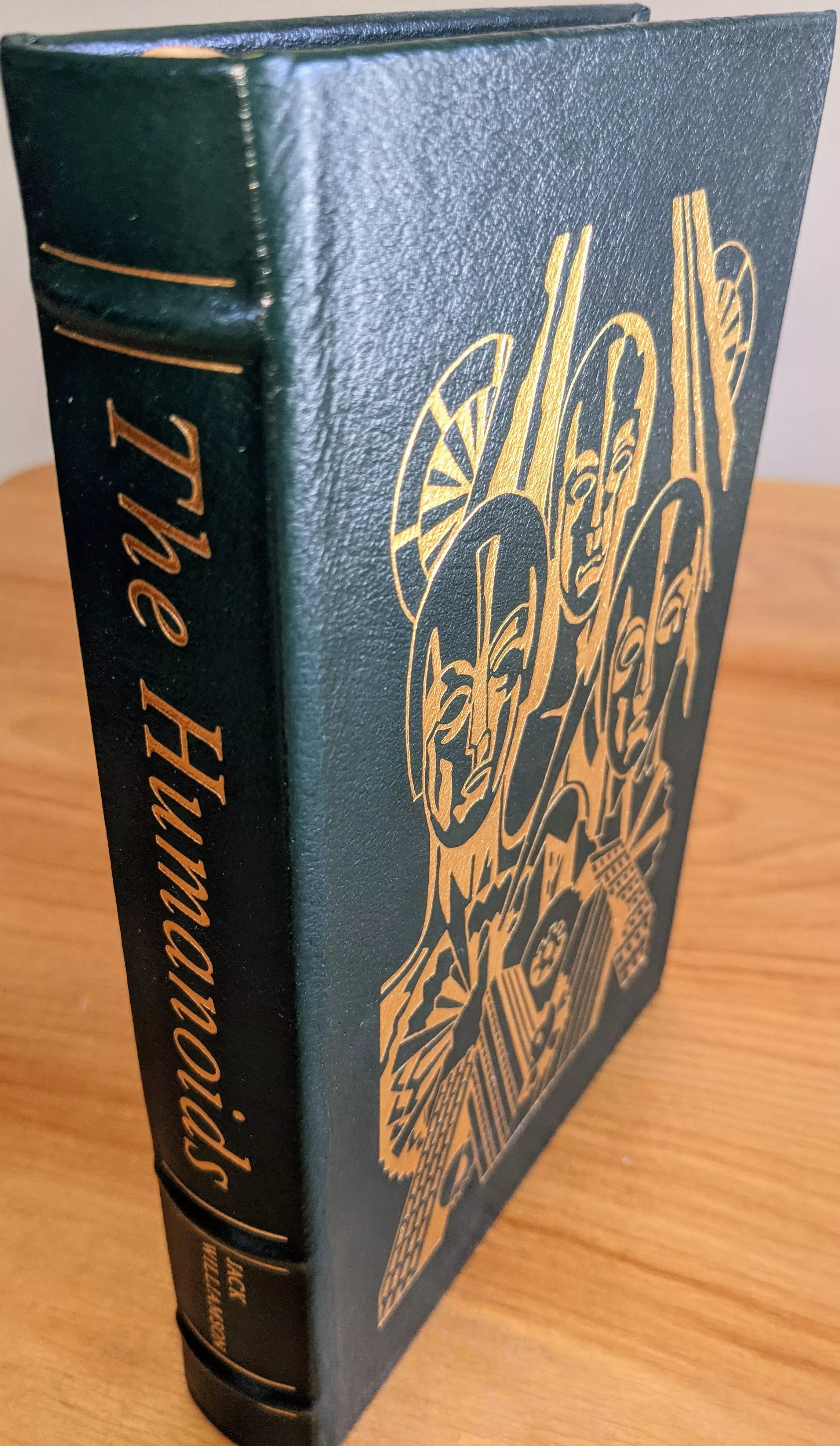 Stunning, pristine, unread collector's edition of The Humanoids by Jack Williamson, from a single private owner. It has always been stored in dust-free bookcases in a dry climate, ensuring its immaculate condition. This is a limited run volume from the Masterpieces of Science Fiction Collection by The Easton Press 
 - 
Bound in beautiful dark green leather, with raised (hubbed) spines and the title The Humanoids and author's name, Jack Williamson, stamped in 22k gold on the spine. The cover features original artwork by David G. Klein, intricately stamped in 22kt gold, depicting stylized humanoid figures with geometric designs and wheel-like motifs behind their heads. Introduction by F.M. Busby
 - 
Printed on archival-quality acid-neutral paper with gilded 22k gold edges, giving the pages a lustrous, reflective finish. It is constructed with smyth-sewn binding and concealed muslin joints, ensuring durability and longevity. The inside of the front cover includes a pristine, unused bookplate. The book's overall condition is pristine, as new, and unread, with no visible wear or damage. This edition is a stunning volume, highly collectible, and ideal for display or preservation in a fine collection